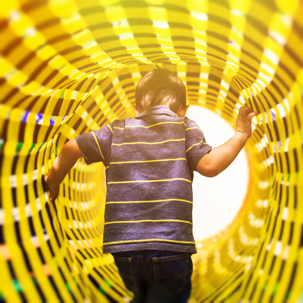 the concept of the transition bridge between the different dimensions of space. a child comes in bright colorful tunnel, view from the back