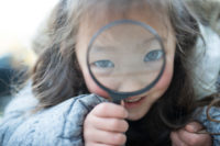 Little girl playing with magnifying glass